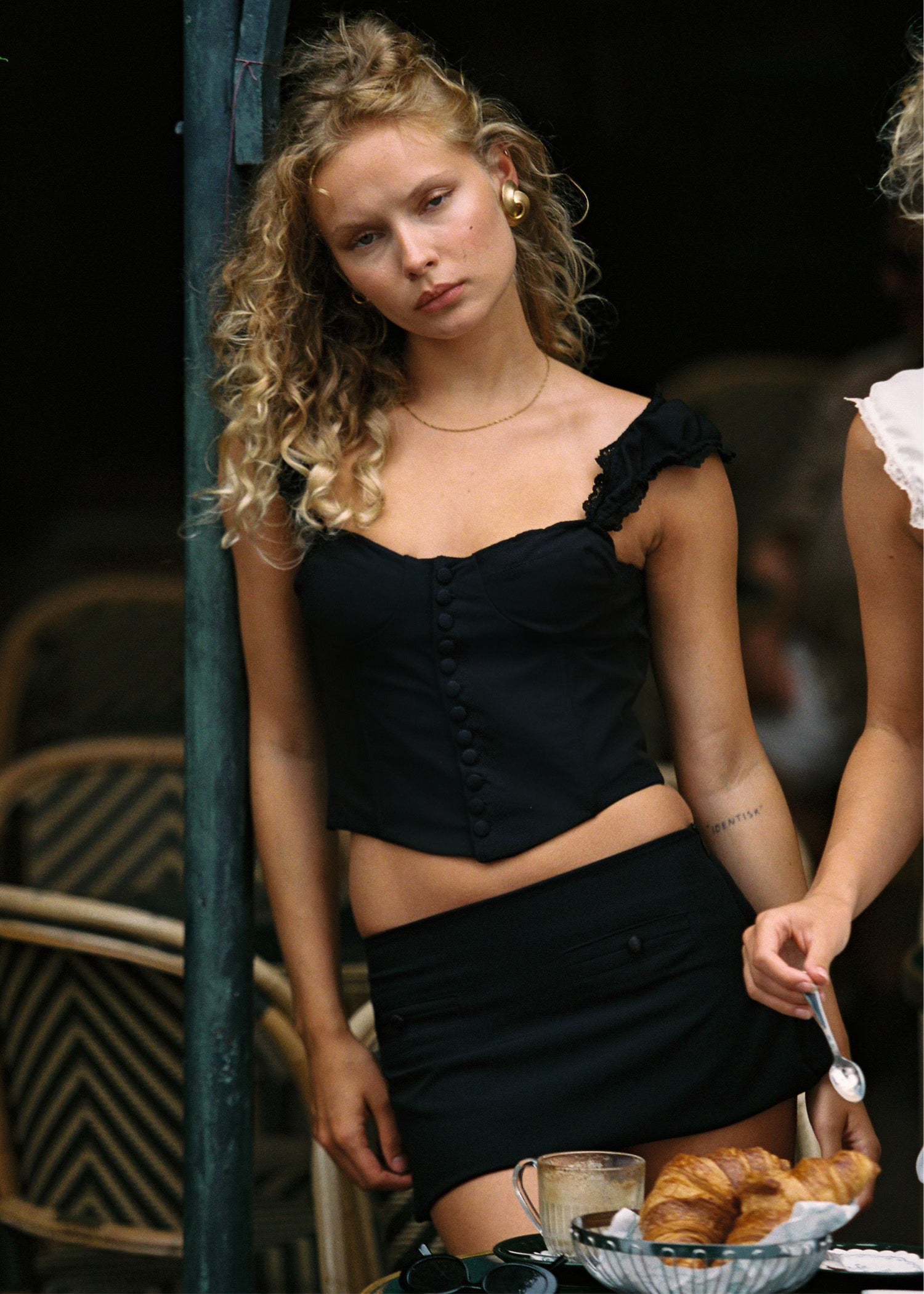 Model wearing black ribbon lace-up corset with satin buttons.