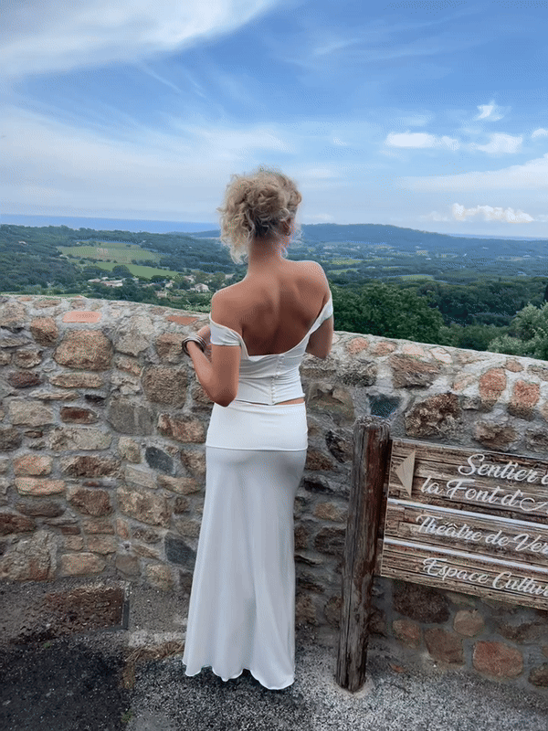Model showcasing the backside of the Riviera Skirt in Ivory, a maxi fold-over skirt featuring ultra-soft fabric, a flattering silhouette, and delicate satin buttons.